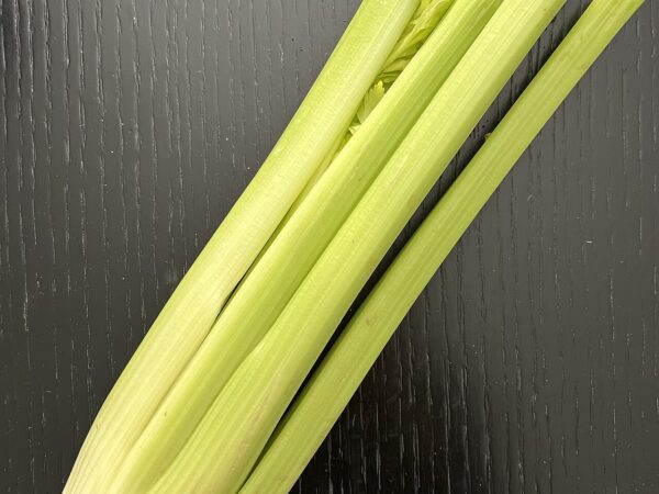 Fresh green celery stalks on a wooden surface