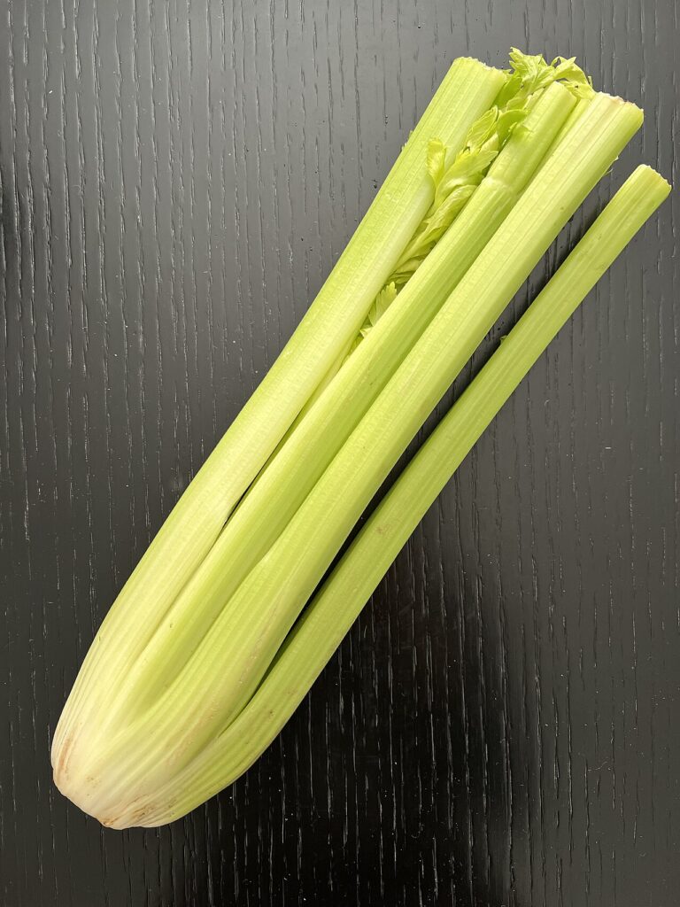 Fresh green celery stalks on a wooden surface
