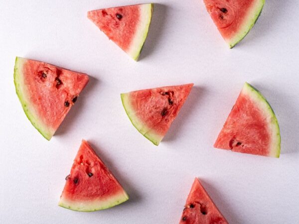 Watermelon wedges with green rind and black seeds laid out on a white background